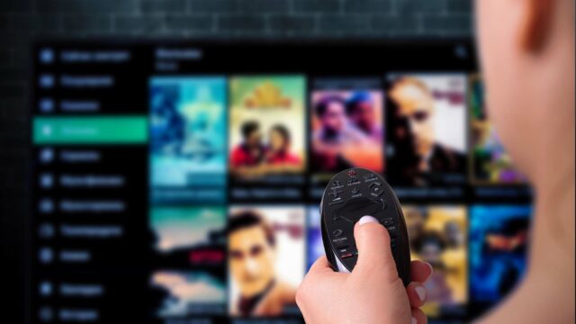 Multimedia streaming concept. woman holds remote control. TV screen with lot of pictures.
